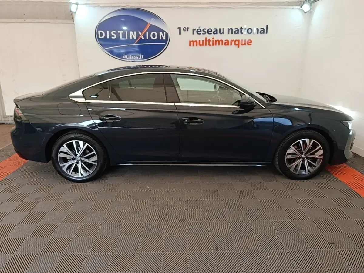 Profil côté gauche d'une Peugeot 508 gris foncé de 2019, avec jantes alliage et vitres teintées, en intérieur showroom.