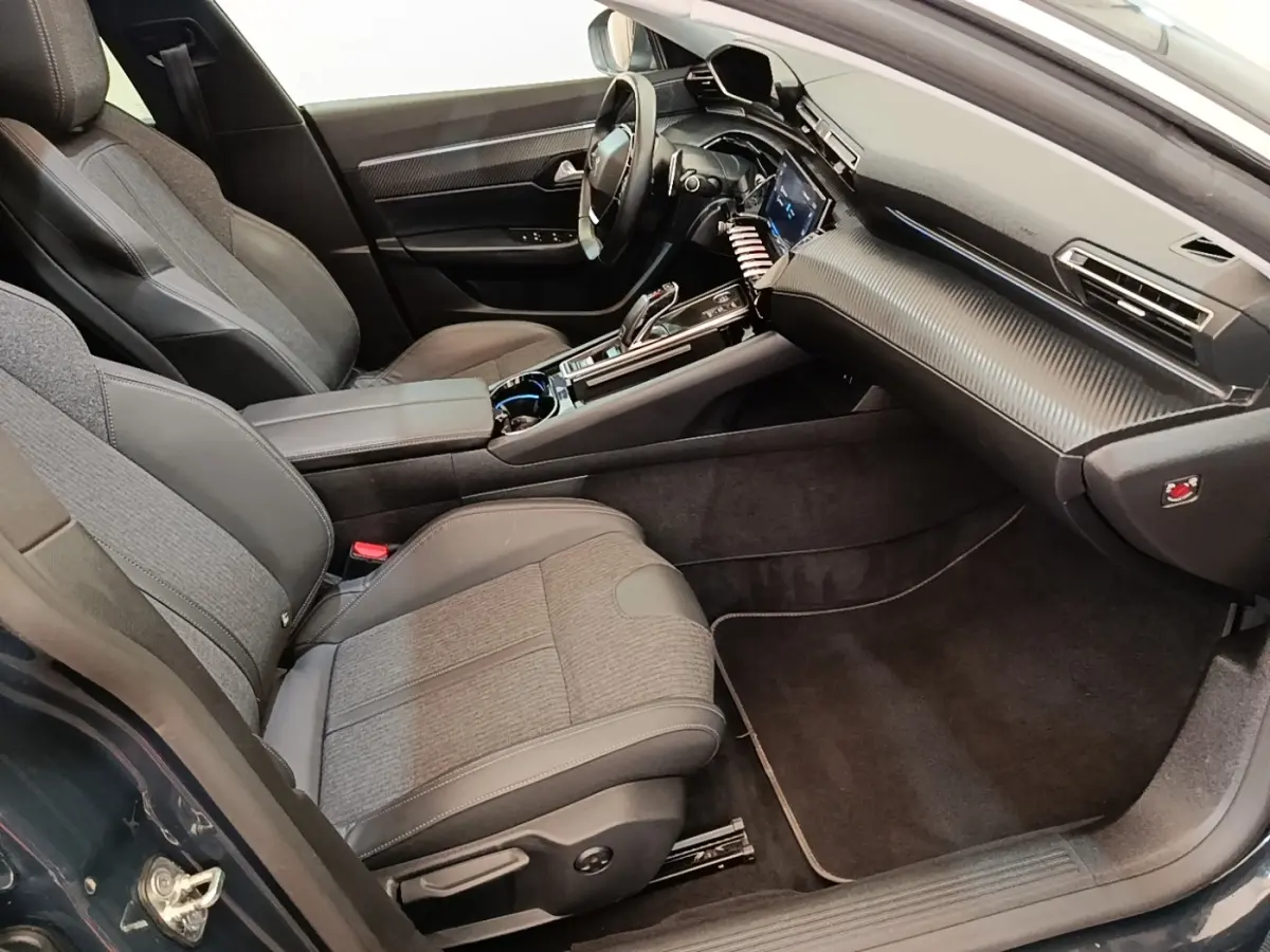 Vue intérieure côté passager de la Peugeot 508 gris foncé, avec tableau de bord moderne et sièges tissu-cuir.