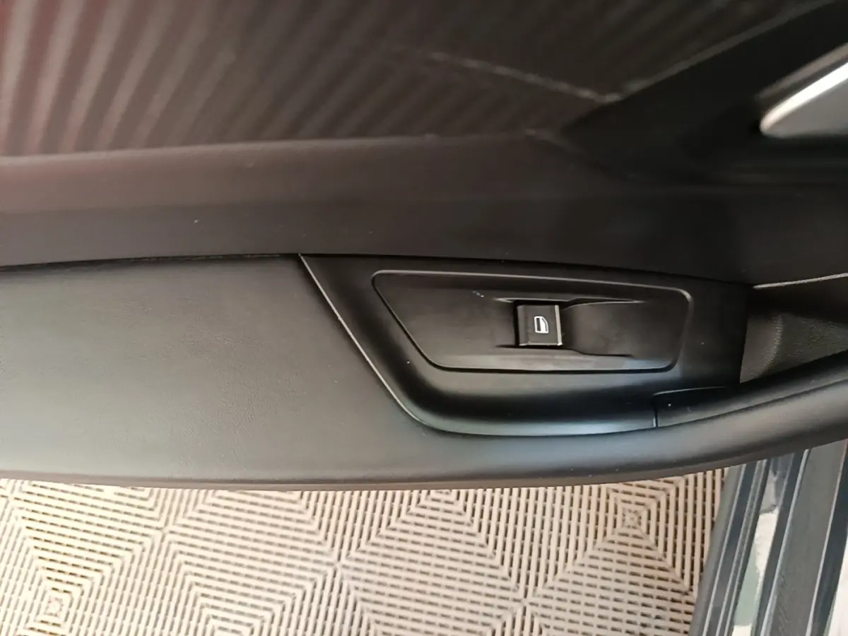 Détail de la commande de lève-vitre côté conducteur sur porte intérieure noire d’une Peugeot 508 gris foncé.