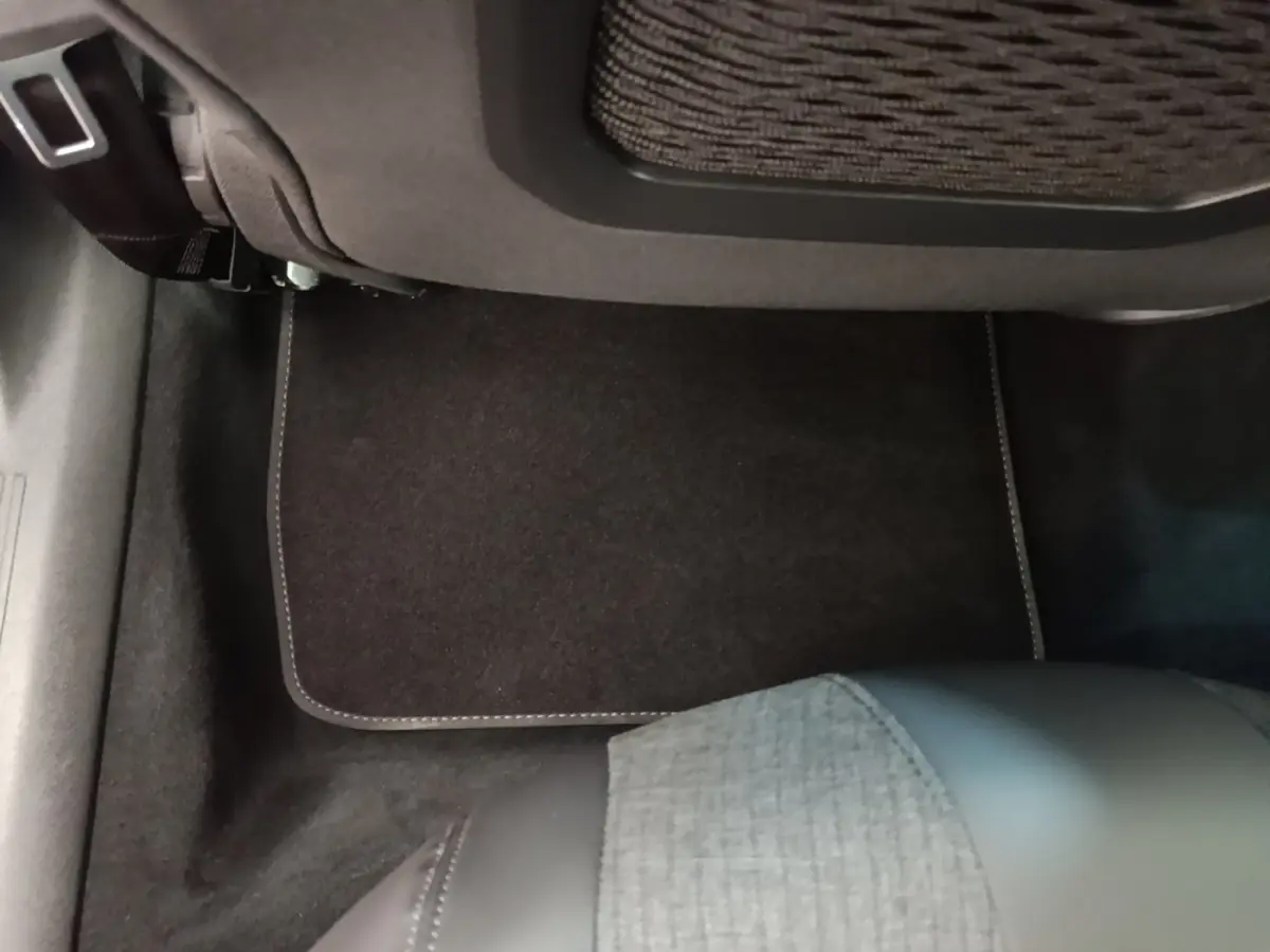 Vue intérieure du plancher arrière droit de la Peugeot 508 gris foncé avec tapis de sol et siège partiel en tissu et cuir.
