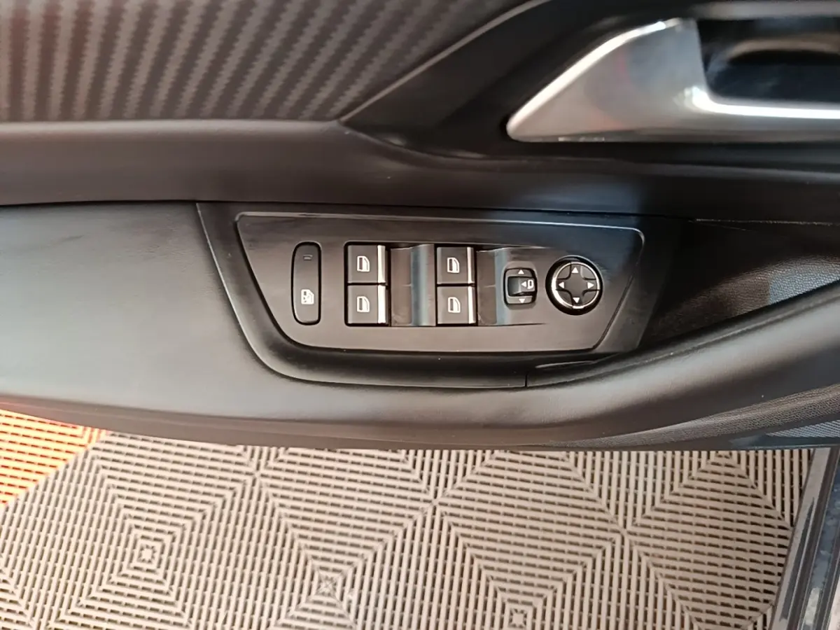 Gros plan sur les commandes de lève-vitres et rétroviseurs côté conducteur d’une Peugeot 508 gris foncé.
