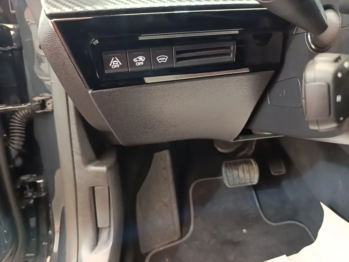 Vue intérieure côté conducteur de la Peugeot 508 gris foncé, avec commandes d'assistance et pédales visibles.