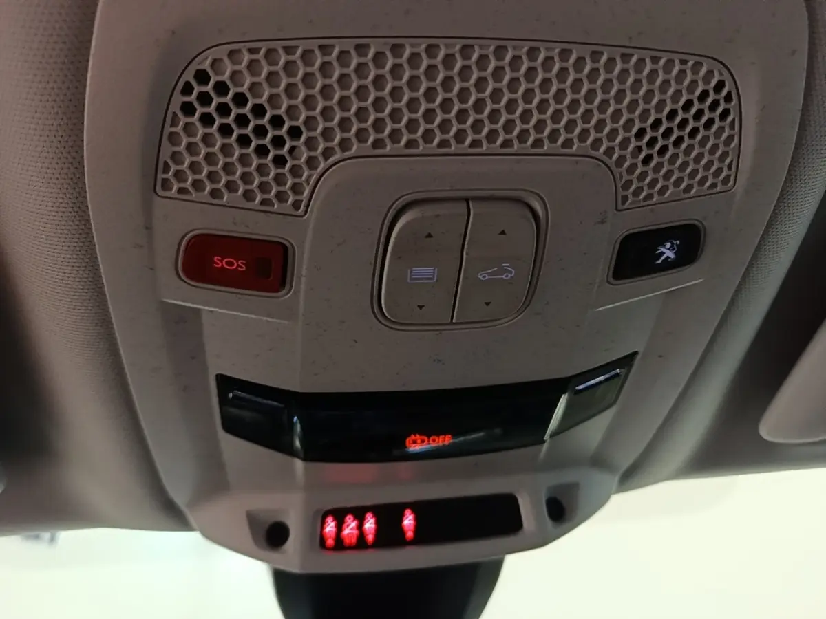Vue en gros plan du plafonnier gris clair avec boutons SOS et ouverture coffre, éclairage rouge allumé dans une Peugeot 508.