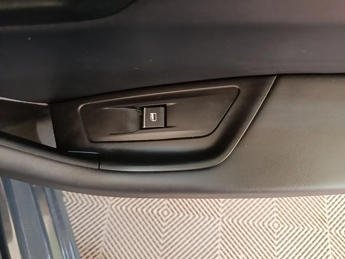 Gros plan sur la commande de lève-vitre côté gauche de la porte intérieure d’une Peugeot 508 gris foncé.
