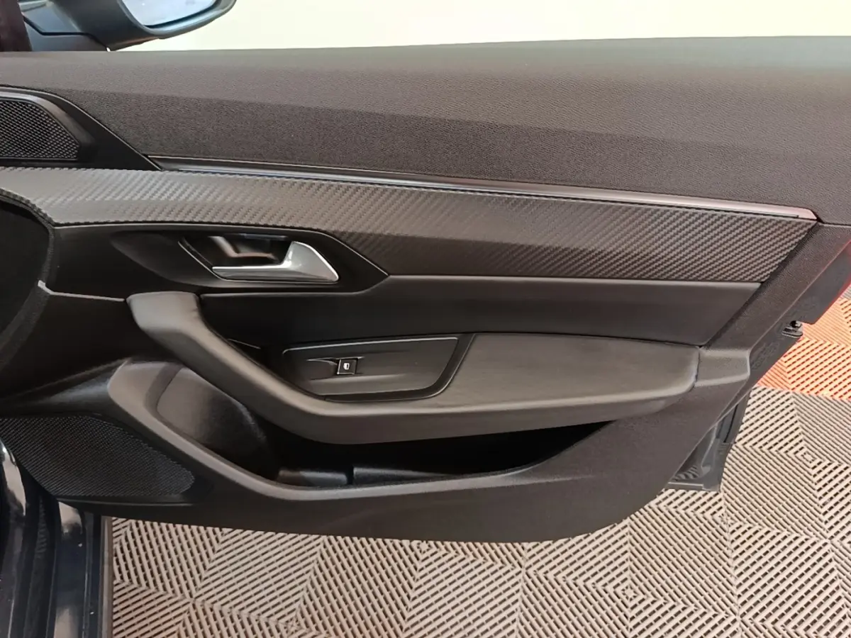 Détail de la porte côté gauche de la Peugeot 508 gris foncé, avec insert effet carbone et poignée argentée.