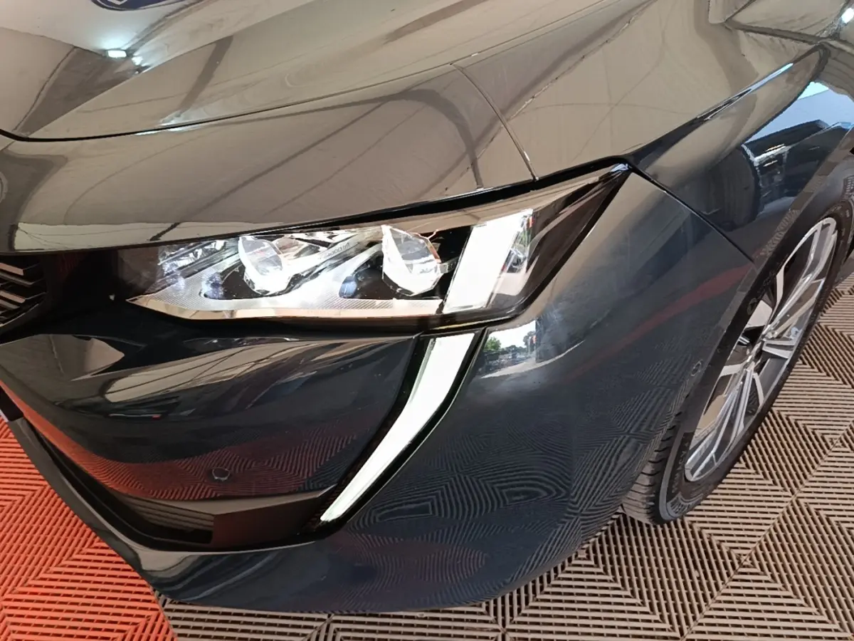Gros plan sur l'avant droit gris foncé de la Peugeot 508 avec ses phares LED et feux diurnes en forme de griffes.