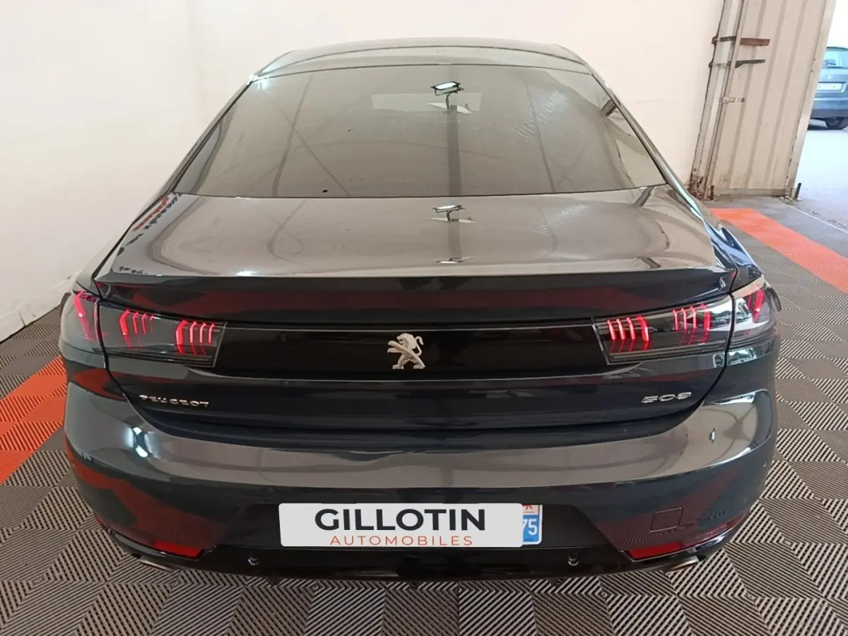Vue arrière d'une Peugeot 508 gris foncé avec feux arrière LED distinctifs et logo lion central.