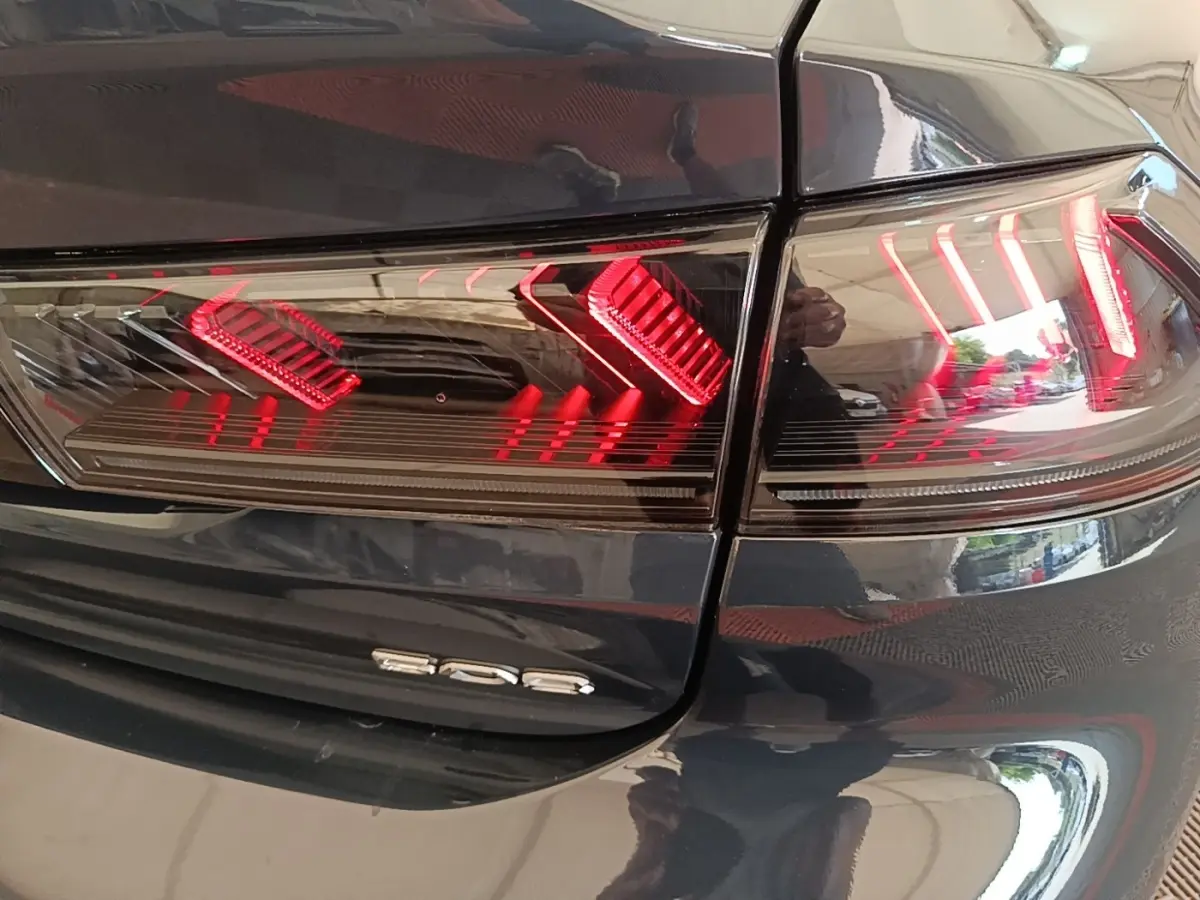 Gros plan sur le feu arrière droit rouge et le logo 508 d’une Peugeot 508 gris foncé, vue arrière.