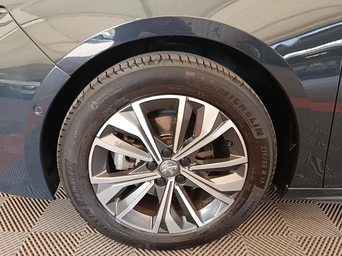 Gros plan sur la roue avant gauche de la Peugeot 508 gris foncé, jante alliage à design moderne et pneus Michelin.