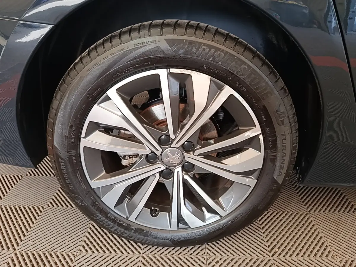 Gros plan sur la roue avant droite d'une Peugeot 508 gris foncé avec jante alliage à multiples branches.