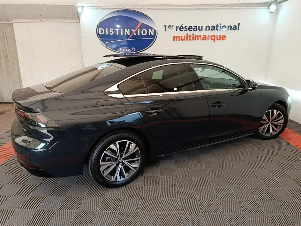 Peugeot 508 gris foncé vue de profil côté gauche, avec jantes alliage et vitres teintées dans un showroom.