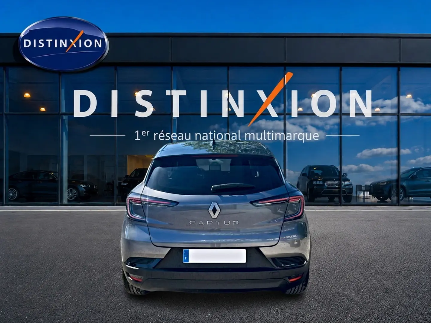 Vue arrière d'un Renault Captur gris cassiopée garé devant une vitrine avec logo Distinxion.