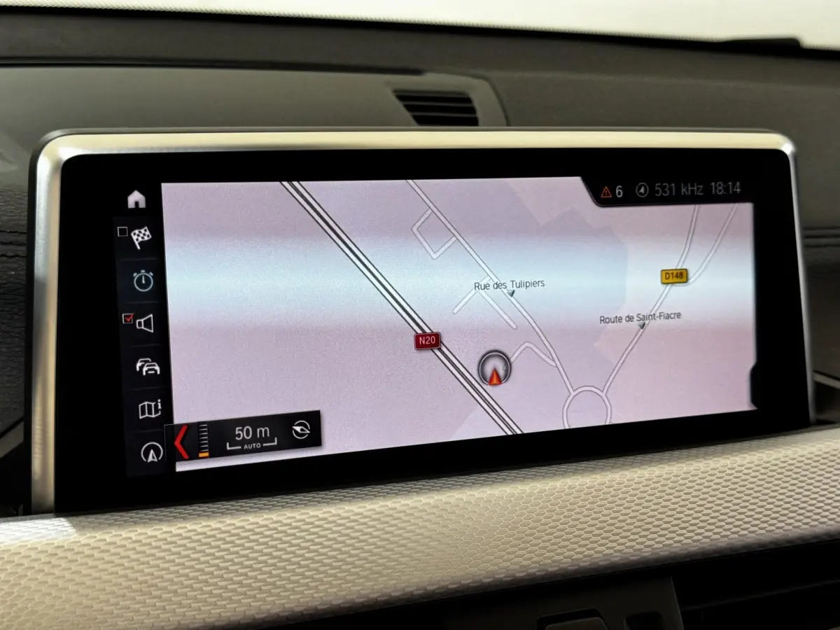 Écran central du système de navigation 3D couleur dans l’habitacle du BMW X2 blanc, vue rapprochée.