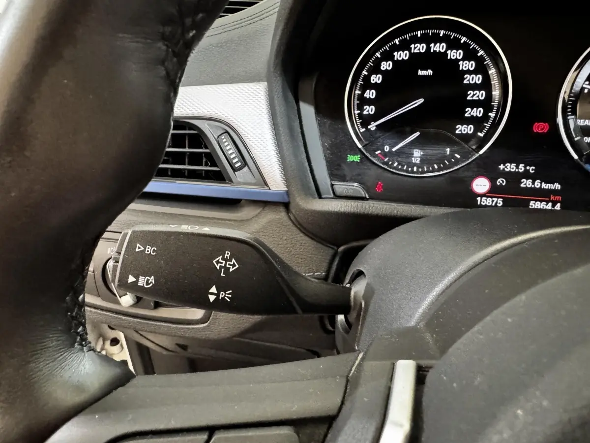 Gros plan intérieur sur le combiné d'instruments et la commande de clignotants du BMW X2 blanc xDrive25e M Sport 2022.