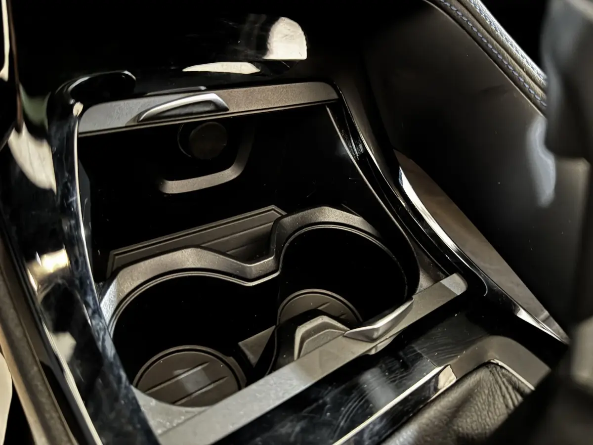 Gros plan sur les porte-gobelets noirs au centre de la console intérieure du BMW X2 xDrive25e blanc.