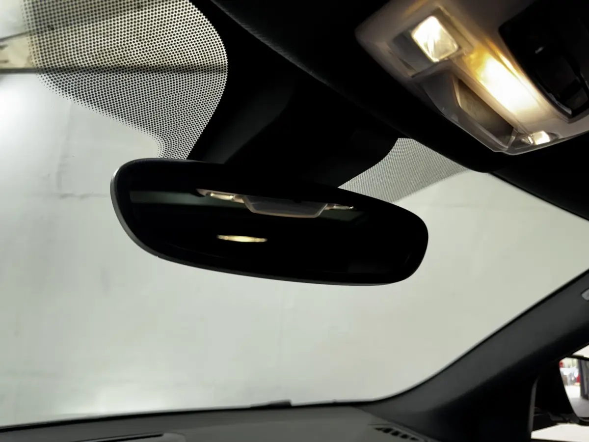 Vue intérieure centrée sur le rétroviseur intérieur et le plafonnier éclairé d’un BMW X2 blanc hybride rechargeable 2022.