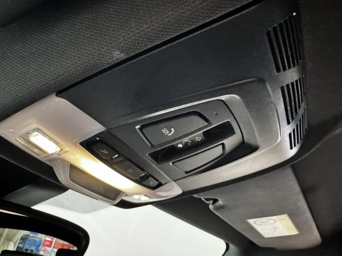 Plafonnier intérieur noir avec commandes SOS et éclairage, vue du toit d’un BMW X2 hybride rechargeable.