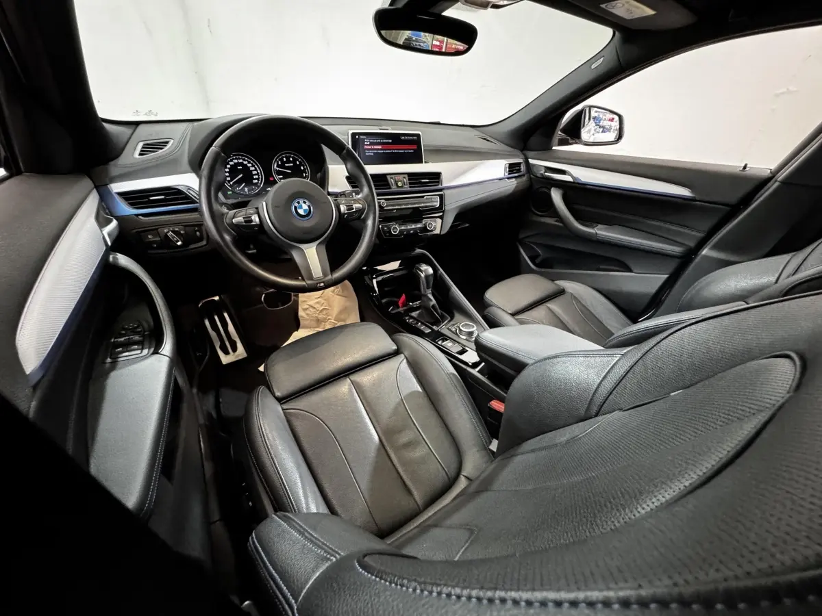 Intérieur noir de BMW X2 xDrive25e 2022 vu côté conducteur, avec tableau de bord moderne et volant multifonction.