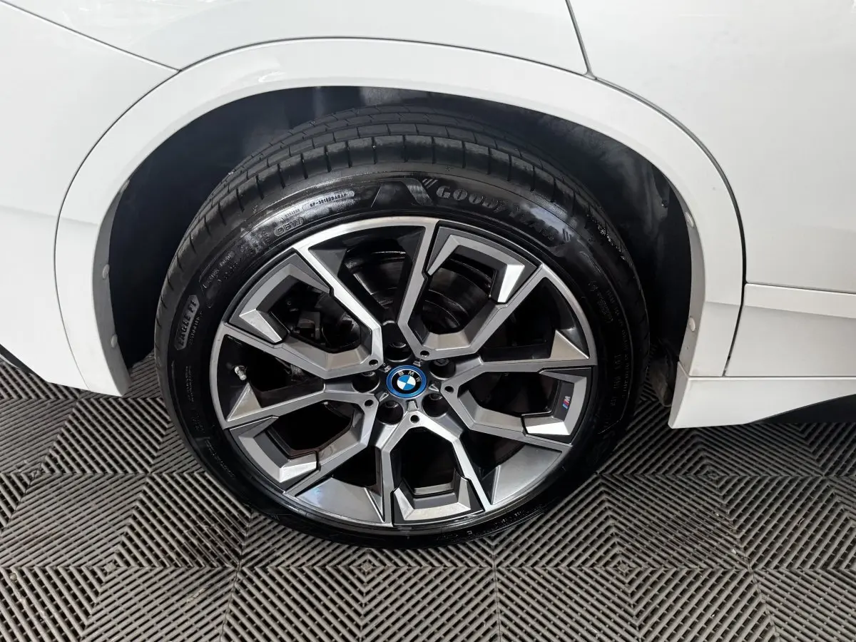 Gros plan sur la roue avant droite d’un BMW X2 blanc, avec jante alliage et logo M Sport visible.