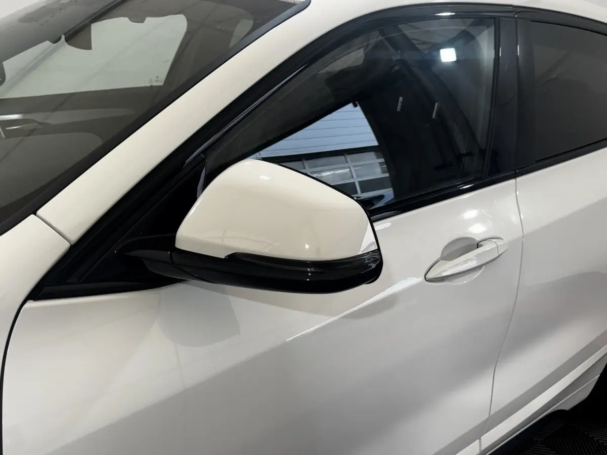 Gros plan sur la porte côté gauche et le rétroviseur blanc d’un BMW X2 xDrive25e M Sport 2022 hybride rechargeable.