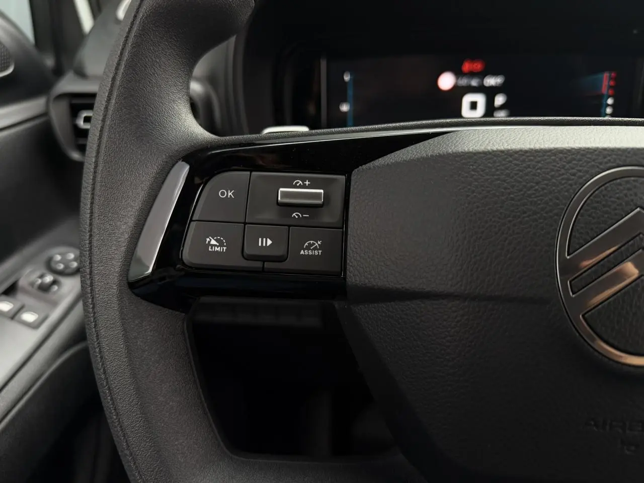 Gros plan sur le volant noir de Citroën Berlingo 2026 avec commandes multifonctions côté gauche et logo central chrome.