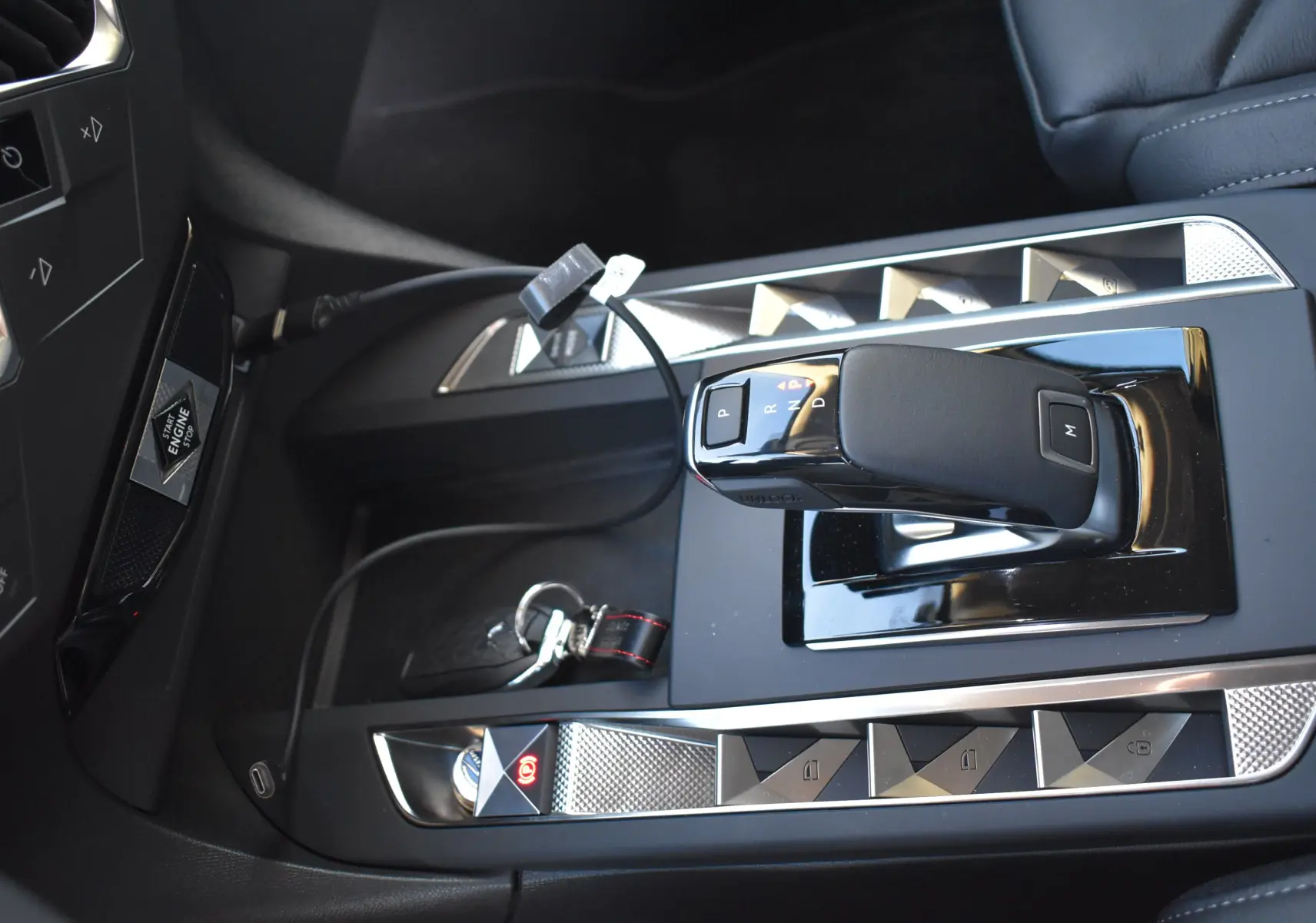 Gros plan sur la console centrale noire du DS3 Crossback 2024, avec levier de vitesses automatique et boutons argentés géométriques.