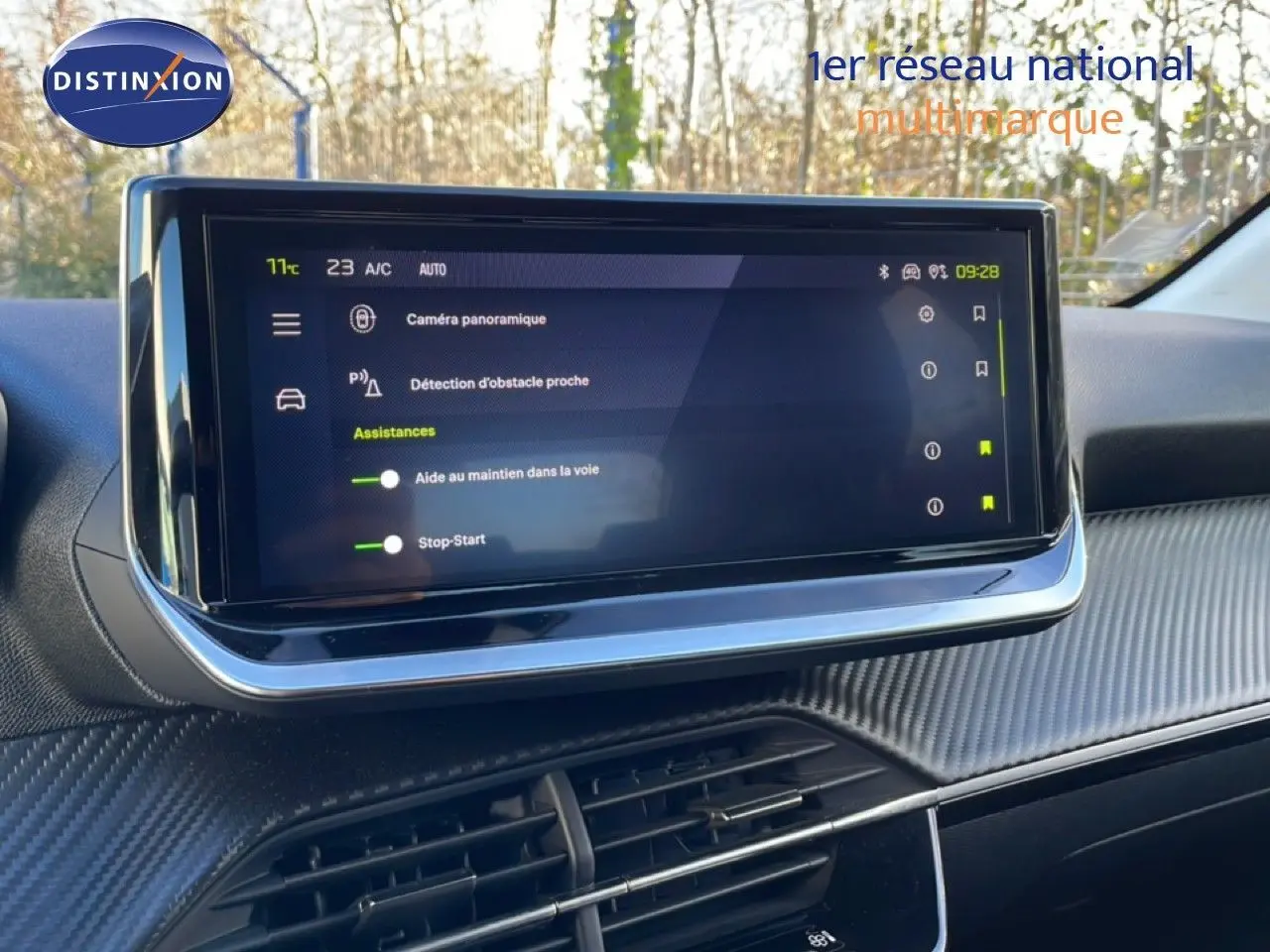 Écran tactile central affichant les aides à la conduite dans l’habitacle d’une Peugeot 208 noire, vue de face.