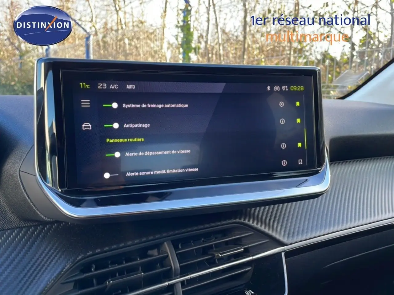 Écran tactile central affichant les aides à la conduite dans l’habitacle d’une Peugeot 208 noire, vue de face.