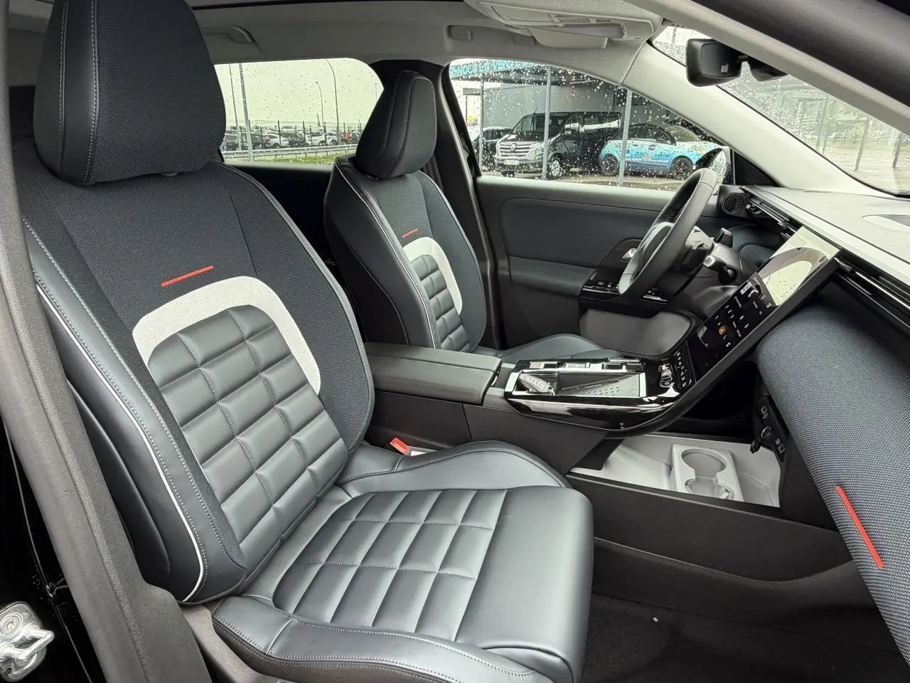 Vue intérieure côté conducteur du Citroën C5 Aircross 2026, sièges noirs matelassés avec inserts gris et touches rouges.