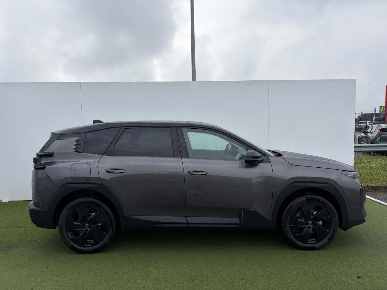 Vue de profil côté gauche d'un Citroën C5 Aircross 2026 gris platinium avec toit noir et jantes alliage noires.