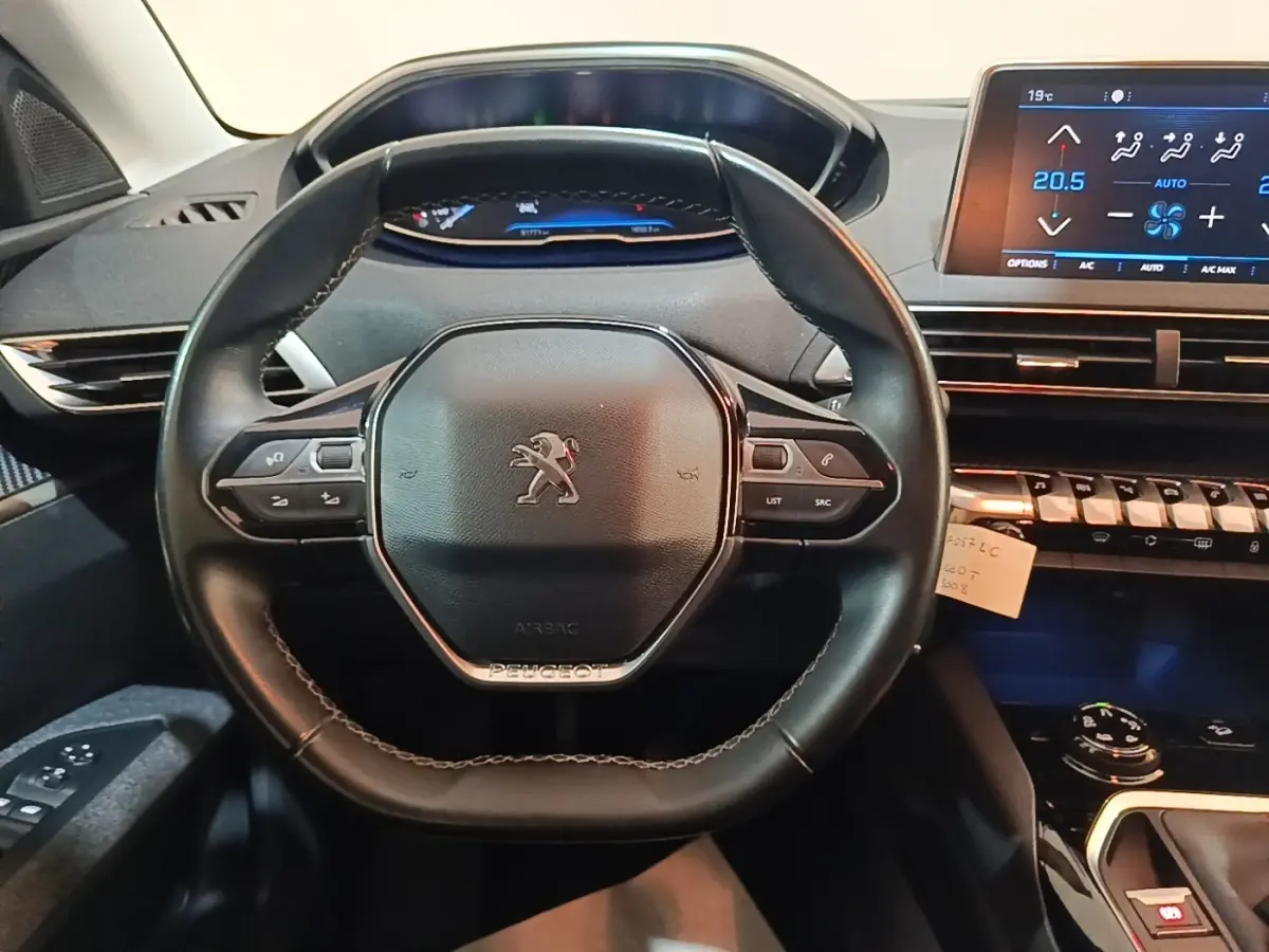 Vue centrée sur le volant cuir noir du Peugeot 5008 2018 avec tableau de bord digital et écran tactile de climatisation.