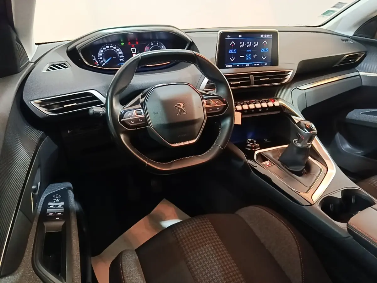 Vue intérieure avant du Peugeot 5008 noir, mettant en valeur le volant cuir multifonctions et l’écran tactile central.