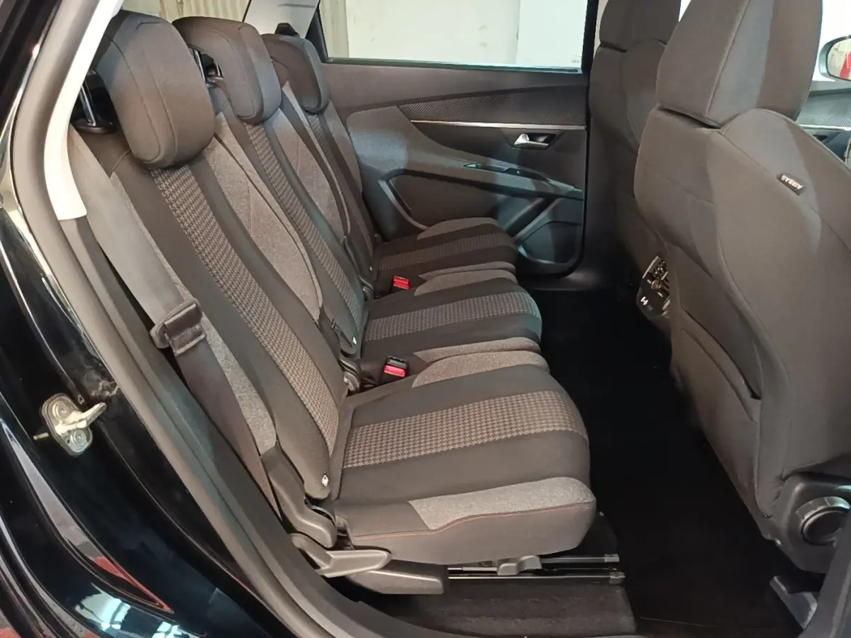 Vue latérale intérieure du siège arrière droit du Peugeot 5008 noir, montrant les trois places individuelles en tissu gris et noir.