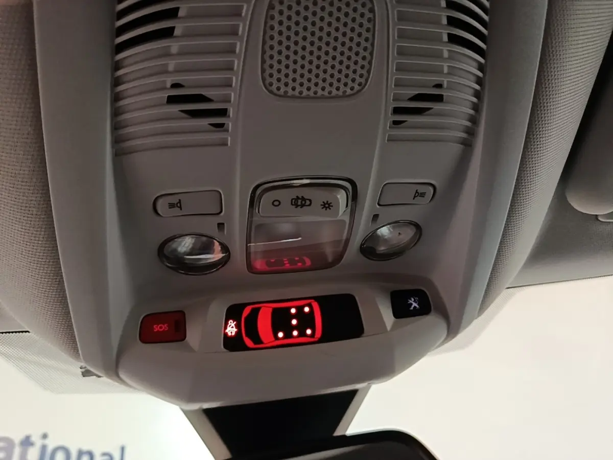 Vue en gros plan du plafonnier intérieur du Peugeot 5008 noir, avec boutons d’éclairage et affichage de porte ouverte rouge.