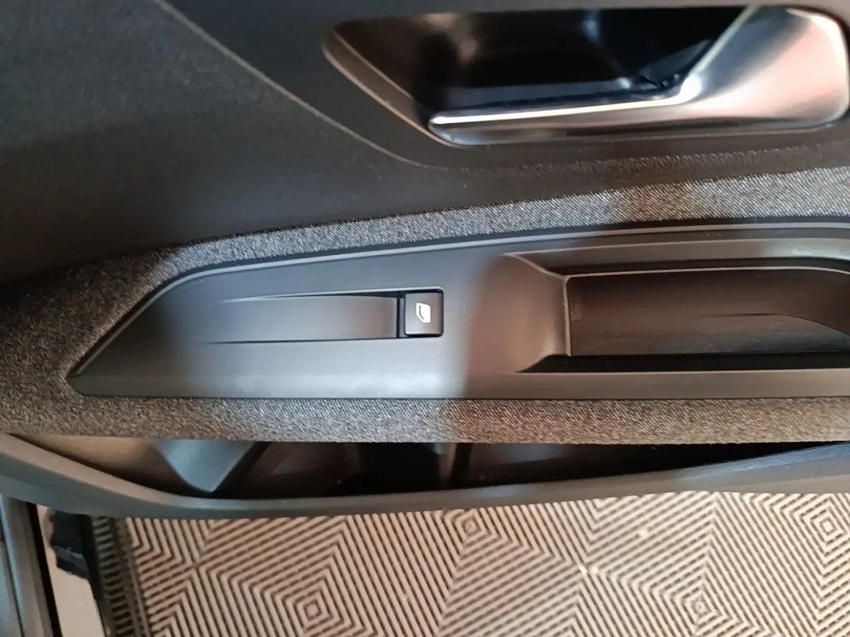 Gros plan sur la poignée intérieure et le bouton de verrouillage de la porte côté conducteur du Peugeot 5008 noir.