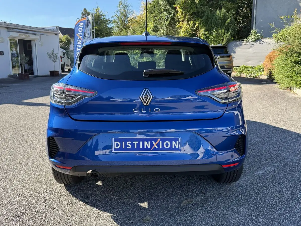 Vue arrière d'une Renault Clio Evolution TCe 90 bleu 2024 avec feux LED et logo distinctif sur parking extérieur.