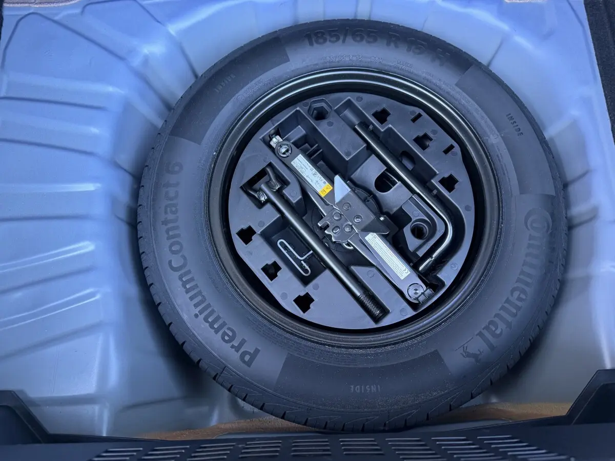 Vue rapprochée de la roue de secours et des outils de bord dans le coffre d’une Renault Clio Evolution TCe 90 bleu 2024.
