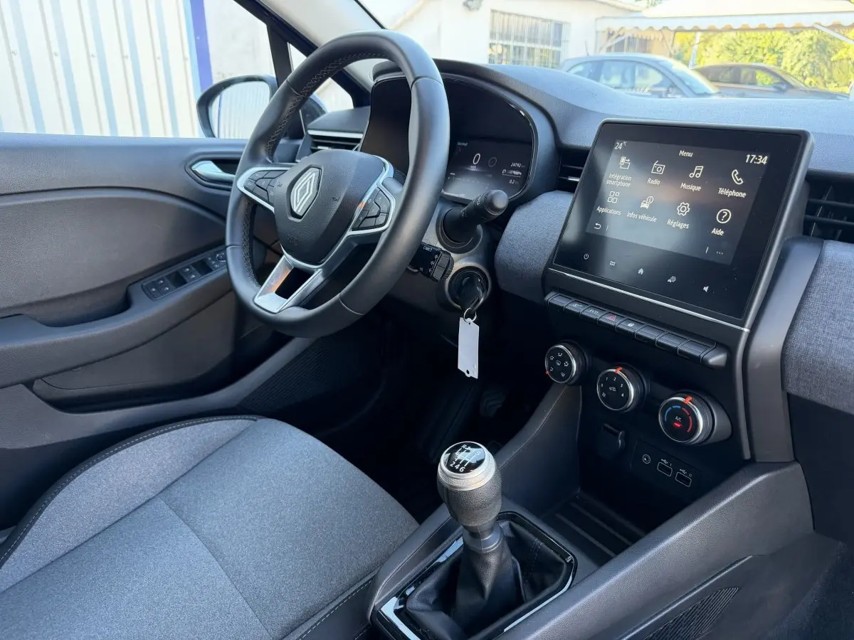 Intérieur Renault Clio Evolution TCe 90 2024 vu côté conducteur, volant cuir, écran tactile 7 pouces et levier de vitesse manuel.