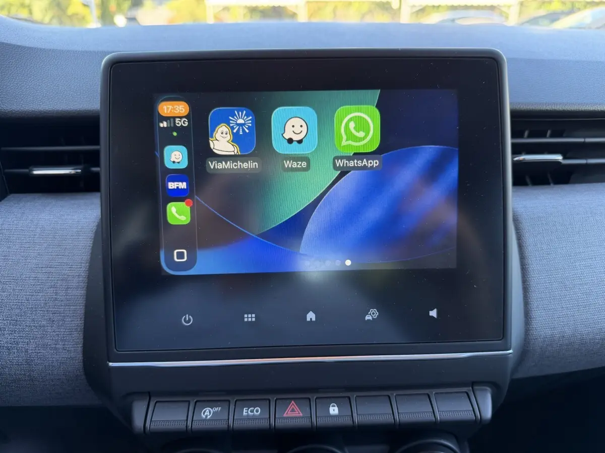 Écran tactile central affichant des applications de navigation et messagerie dans l'habitacle d'une Renault Clio bleu 2024.