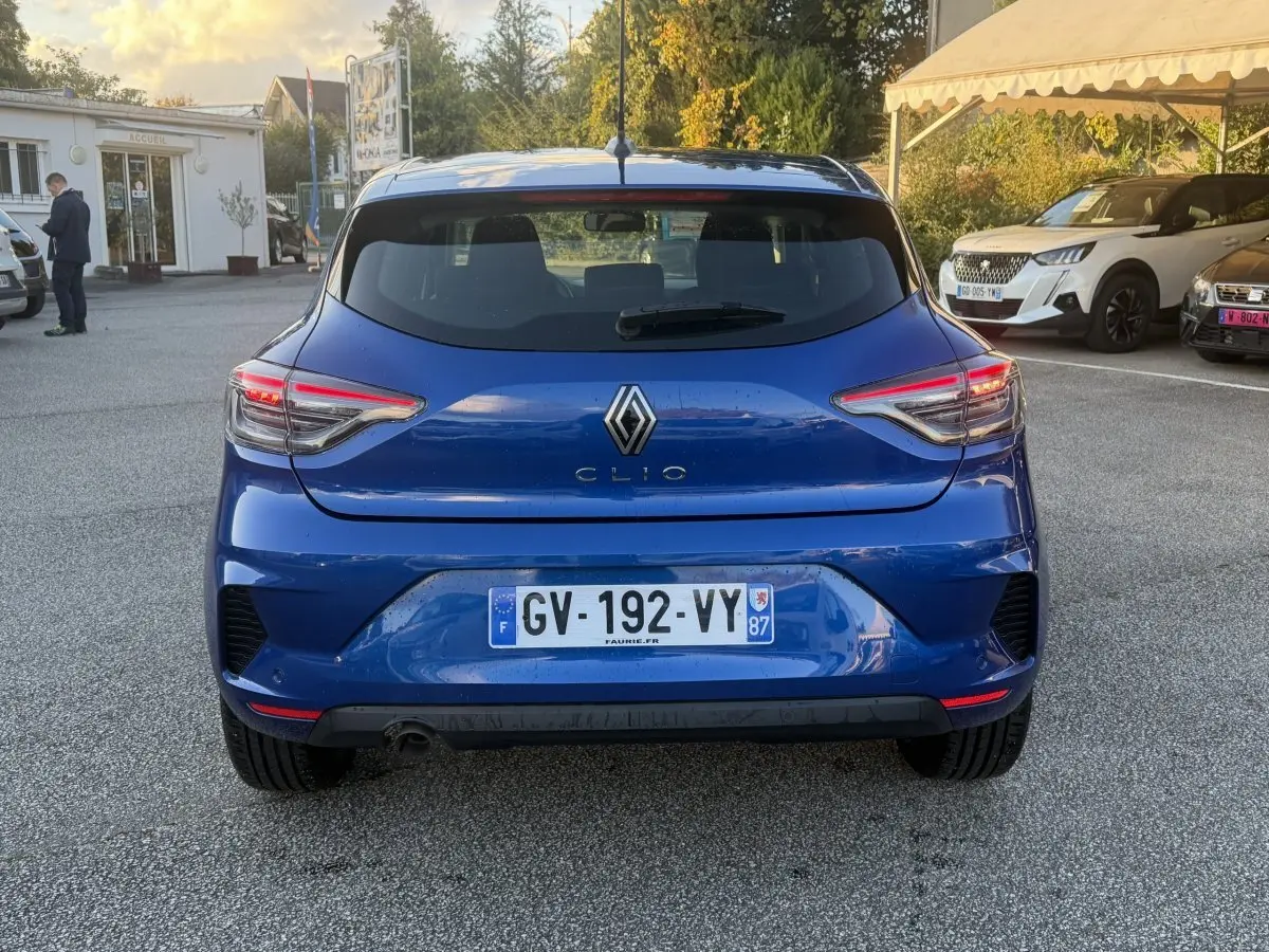 Vue arrière d'une Renault Clio Evolution TCe 90 bleu 2024 avec feux LED et plaque d'immatriculation française.