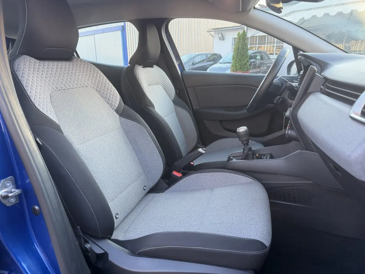 Vue intérieure côté conducteur de la Renault Clio Evolution TCe 90 bleu, sièges tissu gris et console centrale avec boîte manuelle.