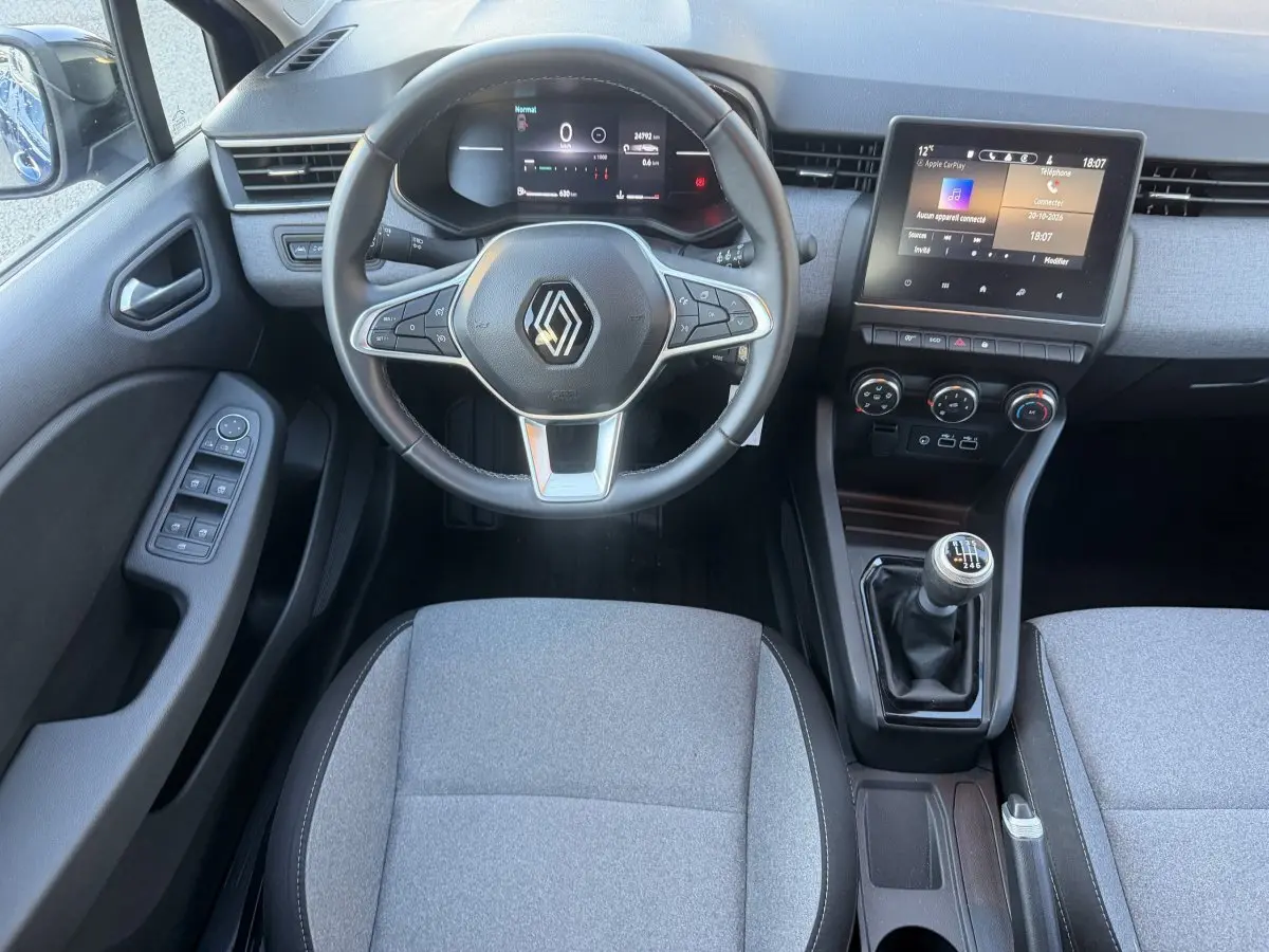 Vue intérieure avant de la Renault Clio Evolution TCe 90 2024, volant cuir, écran tactile et levier de vitesses manuel.