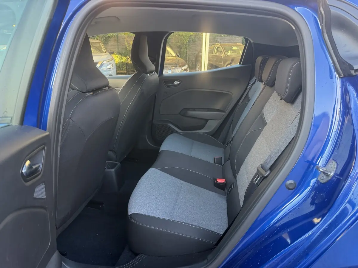 Vue intérieure arrière droite de la Renault Clio Evolution TCe 90 2024 bleu, montrant la banquette 3 places bicolore.