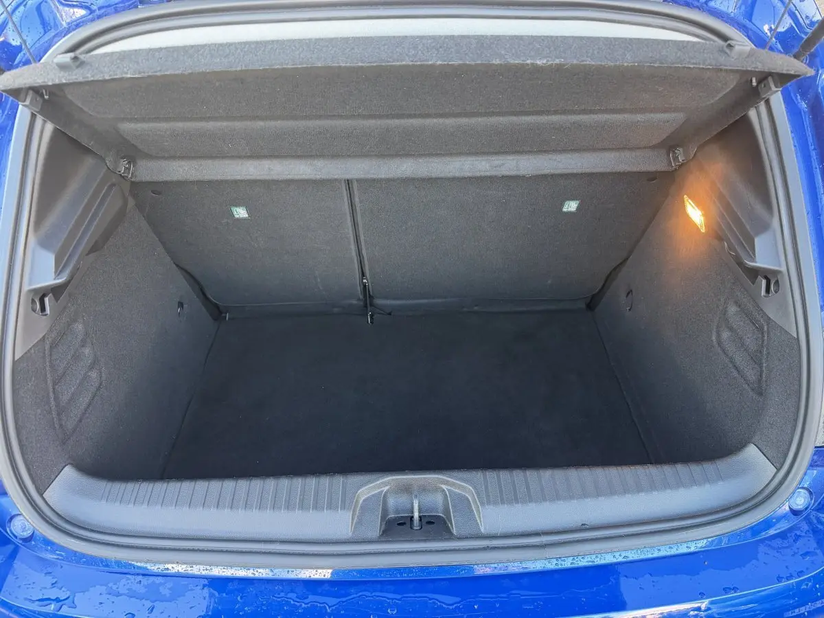 Coffre ouvert vu de dessus d'une Renault Clio Evolution TCe 90 bleu 2024, espace de rangement vide et éclairage intérieur allumé.