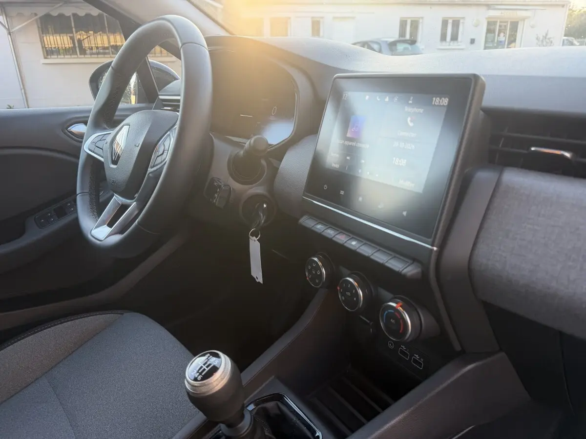 Vue intérieure côté conducteur de la Renault Clio Evolution TCe 90 2024, volant cuir et écran tactile central allumé.