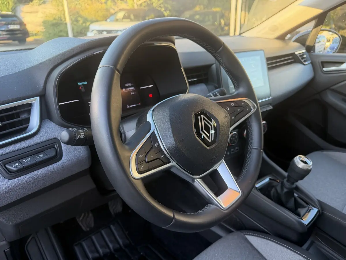 Vue intérieure centrée sur le volant cuir multifonctions et la boîte manuelle de la Renault Clio Evolution TCe 90 2024.