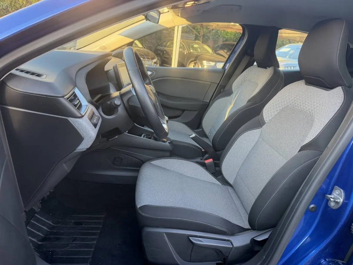 Vue intérieure côté conducteur de la Renault Clio Evolution TCe 90 2024 bleu, sièges tissu gris et noir, volant multifonctions.