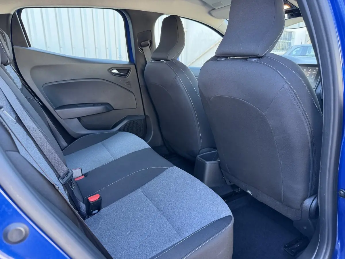 Vue intérieure arrière côté gauche de la Renault Clio Evolution TCe 90 2024 bleu, sièges tissu bicolore gris et noir.