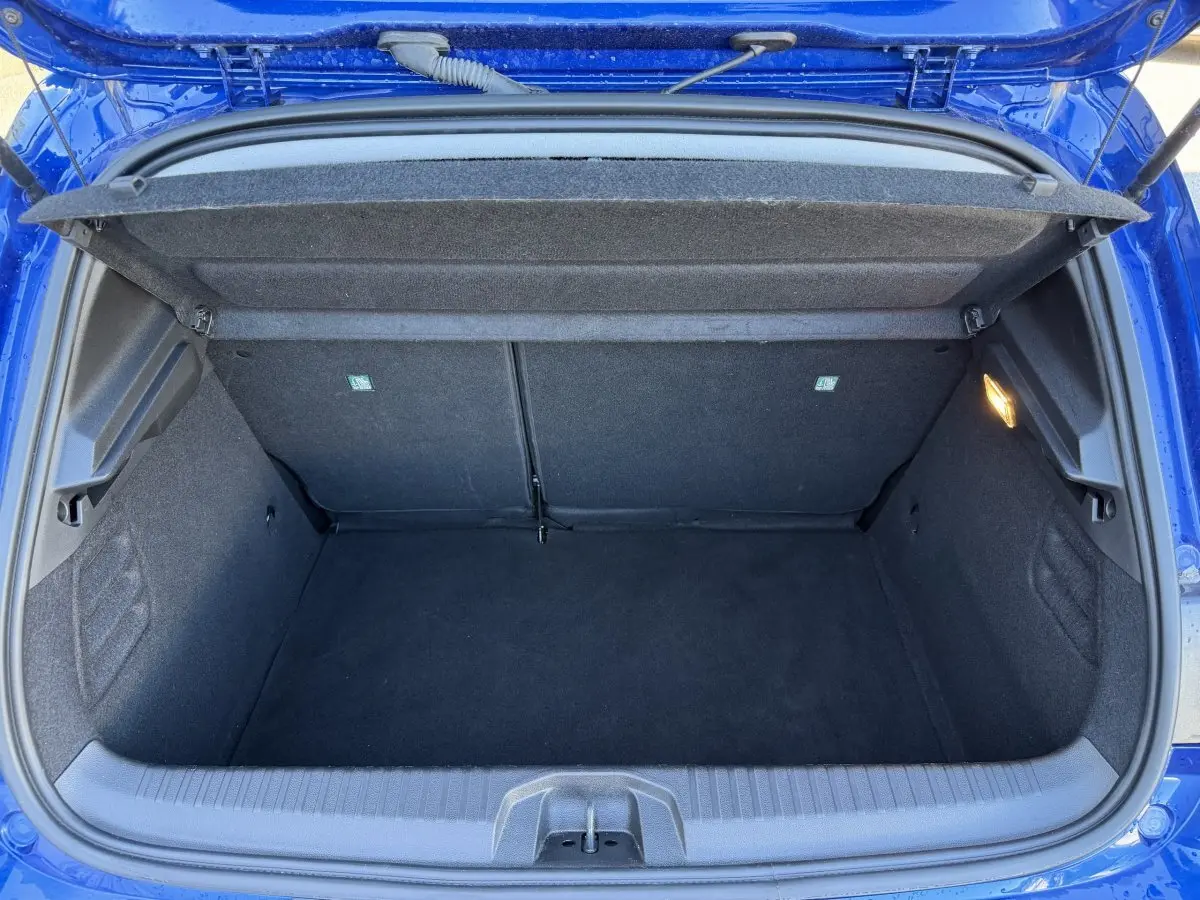 Coffre ouvert vu de dessus d’une Renault Clio Evolution TCe 90 bleu 2024, intérieur noir avec éclairage latéral.