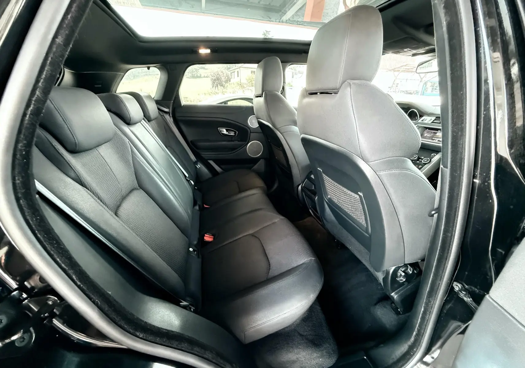 Vue intérieure côté gauche montrant les sièges arrière noirs en cuir et le toit ouvrant du Range Rover Evoque 2017.